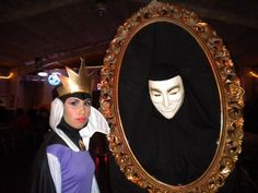 a woman standing next to a mirror with a mask on it