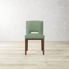 a green chair sitting on top of a hard wood floor next to a white wall