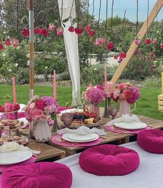 the table is set with pink flowers, plates and napkins on it for an outdoor party