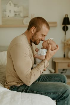 a man sitting on a bed holding a baby