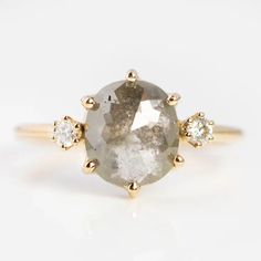 an oval gray diamond ring with three small white diamonds on the band and two yellow gold accents