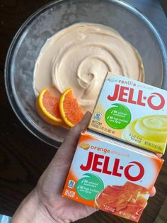 two boxes of jello sitting on top of a table next to an orange slice