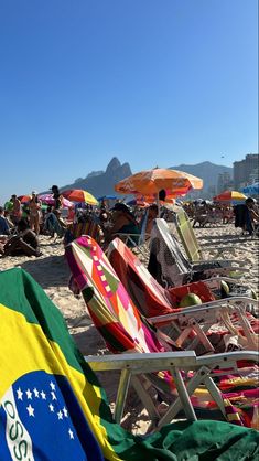 many chairs and umbrellas on the beach with people in the water behind them,