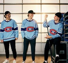 three men in hockey jerseys standing next to each other and one holding a baseball bat