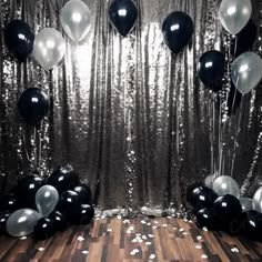 black and white balloons floating in front of a silver curtain with confetti on the floor