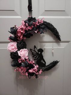 a black and pink wreath hanging on the front door with fairy silhouettes in it