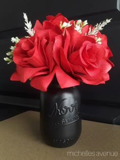 a black vase filled with red roses on top of a table