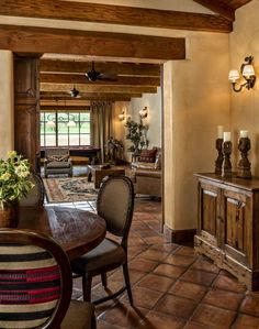 a dining room table and chairs in front of a window with wooden beams on the ceiling