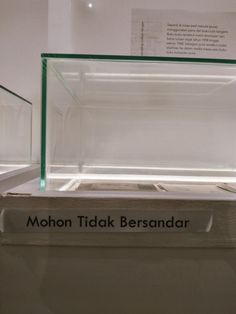 there is a glass display case on the wall with words below it that read mohon tidak besandar