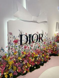 a flower display with flowers and the word dior on it's side in front of a white wall