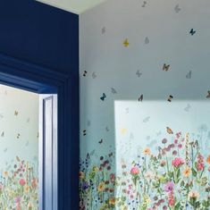 a room with butterflies and flowers painted on the wall next to a blue window frame