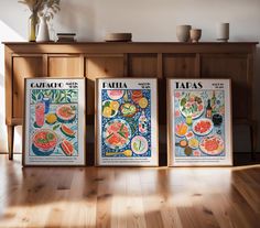 three posters are on the wall in front of a wooden shelf with vases and flowers