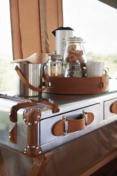 a wooden spoon sitting on top of a metal tray filled with coffee pots and other items