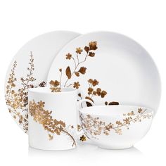 a white and gold dinnerware set with flowers on the front, two cups and one saucer