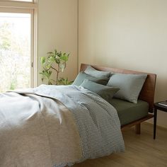 a bed sitting in a bedroom next to a window with a plant on top of it