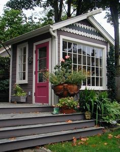 a small house with potted plants on the steps