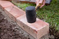 a person using a hammer to put bricks in the ground