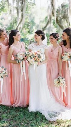 a group of women standing next to each other wearing dresses and holding bouquets in their hands