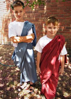 two young boys standing next to each other in front of a brick wall and tree