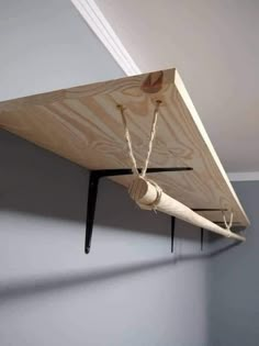 a piece of wood is hanging from the ceiling with ropes attached to it and two wooden pegs on each end