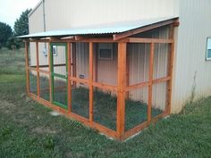 a small chicken coop in the grass next to a building