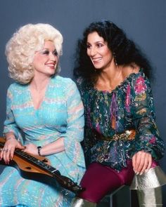 two women sitting next to each other with musical instruments in their hands and smiling at the camera