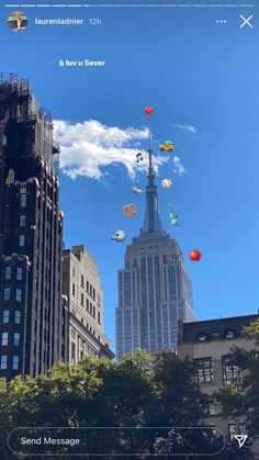 there are many kites flying in the sky above some tall buildings on a sunny day