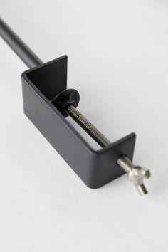 a black metal object on a white surface with a screw in the middle and two keys attached to it