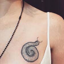 a woman's chest with a small tattoo of a snail on the left side