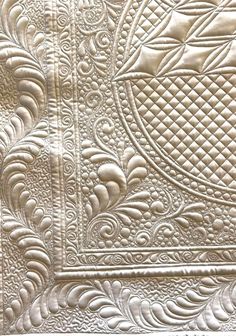 an intricately designed quilting pattern on the side of a white piece of cloth