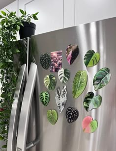 a stainless steel refrigerator covered in magnets and plants