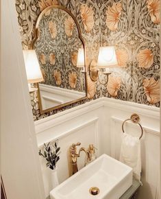 a white sink sitting under a bathroom mirror next to a wall mounted faucet