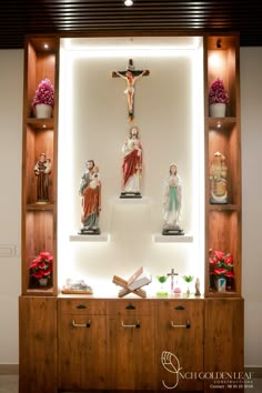 the crucifix is on display in front of some wooden shelves with flowers