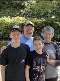 a group of people standing next to each other in front of some trees and bushes