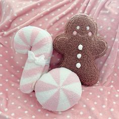 two gingerbread cookies and a candy cane on a pink bed sheet with polka dots