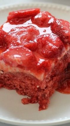 a piece of cake with strawberries on top is sitting on a white plate and covered in sauce