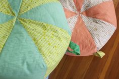 two colorful pillows sitting on top of a wooden floor