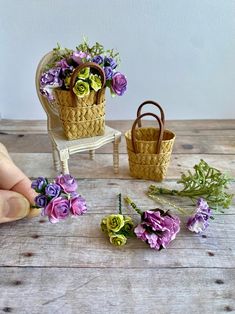 miniature flowers are placed in baskets on a wooden table next to a handmade chair