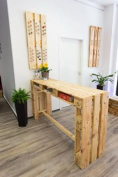 a desk made out of wooden pallets in a room with potted plants on the floor