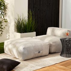 a large white couch sitting on top of a wooden floor next to a planter