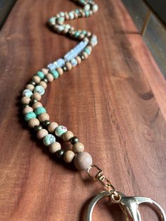 a wooden table topped with a necklace and two pairs of scissors on top of it