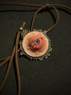 💚Get ready for Halloween with this extraordinary handmade clay eye pendant necklace! This unique piece is a must-have for anyone who loves gothic and unconventional jewelry, especially during the spookiest time of the year. The pendant features a realistic, intricately detailed eye set in a vintage-inspired brass frame, suspended on an adjustable suede cord. It's the perfect accessory to add a creepy yet stylish touch to your Halloween costume or everyday gothic attire.💚 📣Features📣    Material: High-quality clay, brass pendant frame, suede cord   Pendant Size:   35 mm   Cord Length:    90 cm   Handcrafted: Each piece is meticulously handmade, making every necklace unique   Design: Realistic eye with intricate details and lifelike appearance, perfect for Halloween and gothic fashion   V Handmade Resin Jewelry For Halloween, Gothic Clay Jewelry, Handmade Polymer Clay Halloween Jewelry, Unique Hand Cast Halloween Necklaces, Unique Hand Cast Halloween Necklace, Handmade Halloween Necklace, Eyeball Necklace, Unconventional Jewelry, Gothic Attire