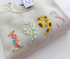 a white sweatshirt with embroidered numbers and flowers on it