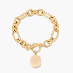 Are you looking to add a personalized touch to your everyday look? The Hadley Toggle Bracelet is here to meet your needs. With a link chain and dainty pendant crafted from dazzling gold, this beautiful and simple piece will add a powerful statement to your look. Experience the perfect balance between elegance and functionality with the Hadley Toggle Bracelet. Available in 14k gold plated brass Pendant size: 3/4" by 1/2" 7" link chain Toggle closure With engraving this item is FINAL SALE SKU: BYB Tennis Jewelry, Dainty Pendant, Customized Jewelry, Custom Charms, Toggle Bracelet, Brass Pendant, Turquoise Jewelry, Birthstone Jewelry, Link Chain