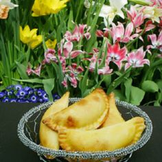 some kind of food that is in a bowl on a table with flowers behind it