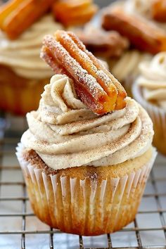 cupcakes with frosting and bacon on top sitting on a wire cooling rack