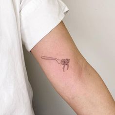 a person with a tattoo on their arm is holding a spoon in the other hand