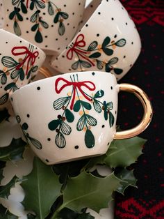 christmas themed cups and saucers with holly on them