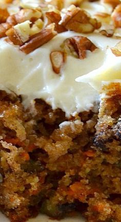 a piece of carrot cake with white frosting and nuts