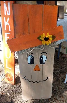 a wooden block with a scarecrow face and sunflower on it's head